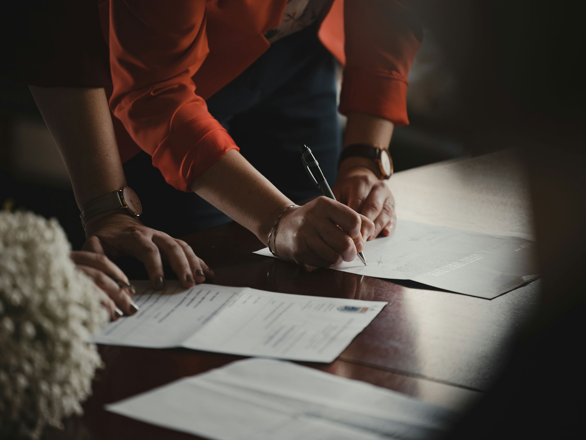 person-in-orange-long-sleeve-shirt-writing-on-white-paper.jpg person in orange long sleeve shirt writing on white paper